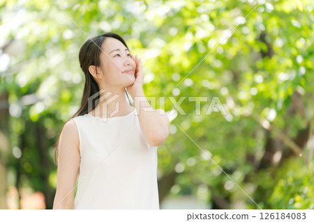 Portrait of a woman in her twenties standing in a summer park Portrait of a woman in her twenties standing in a summer park 126184083