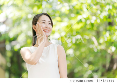 Portrait of a woman in her twenties standing in a summer park 126184355