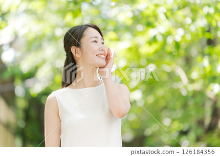 Portrait of a woman in her twenties standing in a summer park Portrait of a woman in her twenties standing in a summer park 126184356