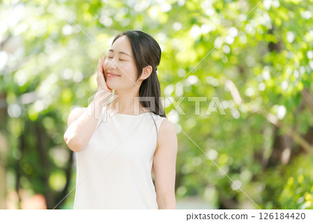 Portrait of a woman in her twenties standing in a summer park 126184420