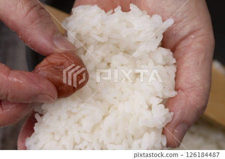 The process of putting pickled plums into the rice balls and making them 126184487