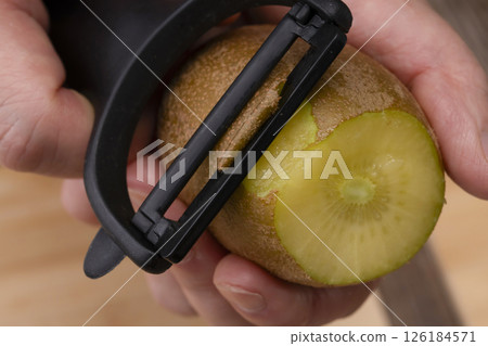 Peel the skin of the gold kiwi fruit with a peeler. Peel the skin of the gold kiwi fruit with a peeler. 126184571