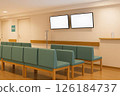 The waiting area in front of the examination room features sofas and two digital monitors mounted on the wall. 126184737