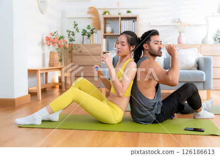 Young asian couple resting together after home workout in living room at home. 126186613