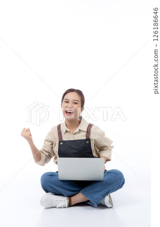 Portrait young asian business woman wearing apron holding laptop computer isolated. 126186646