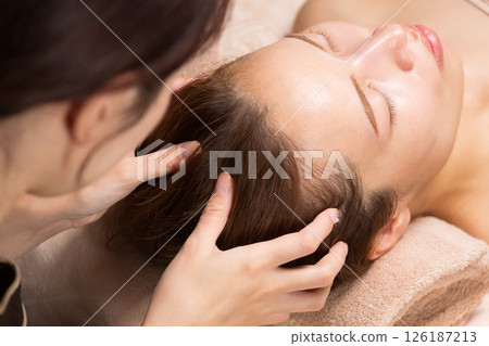 Young asian beautician doing head massage. Young asian beautician doing head massage. 126187213