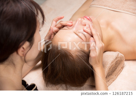 Young asian beautician doing facial massage. 126187215