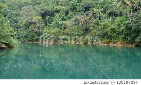 Boat cruises a peaceful jungle river under the midday sun, surrounded by vibrant greenery and calm waters Boat cruises a peaceful jungle river under the midday sun, surrounded by vibrant greenery and calm waters 126187857