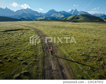Aerial view of woman trail runner in high altitude mountains Aerial view of woman trail runner in high altitude mountains 126187932