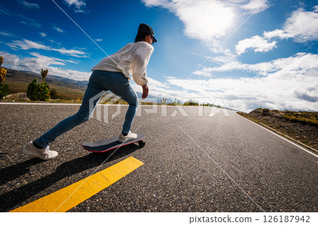 Skateboarder skateboarding on the mountain road 126187942
