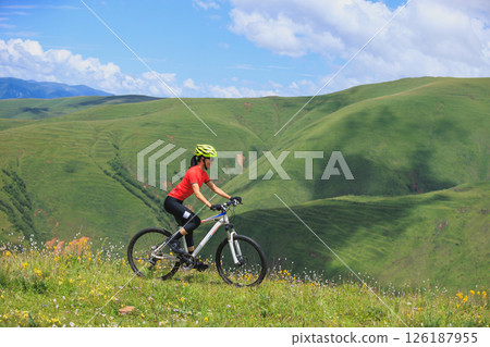 Fitness aisan woman riding mountain bike on beautiful flowering grassland mountain top 126187955