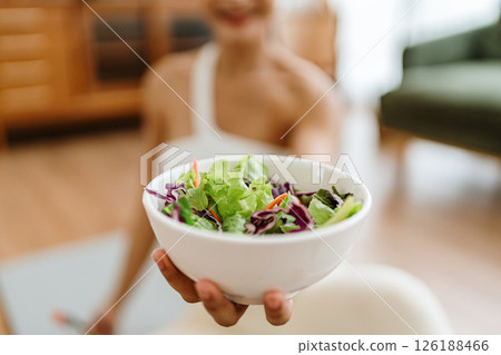 Healthy Asian Woman Enjoying Fresh Salad at Home After Yoga Workout 126188466