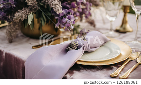Elegant wedding table with floral centerpiece, gold accents and purple lavender details 126189061