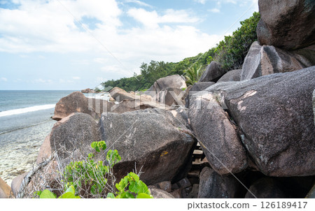 View of rough trail with wooden planks passing under large granite boulders 126189417