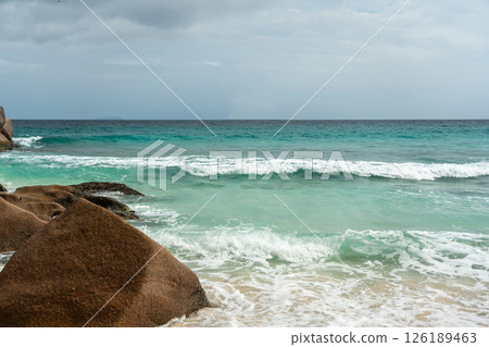 Ocean and sea wave crash against rock and water along the beach shore under the blue sky Ocean and sea wave crash against rock and water along the beach shore under the blue sky 126189463