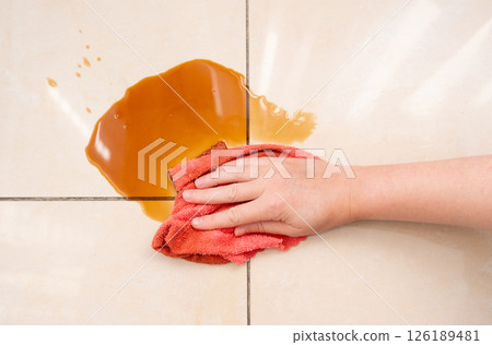Spilled coffee, coffe puddle stain on tiled floor, messy leak with fallen cup, brown drink spillage 126189481