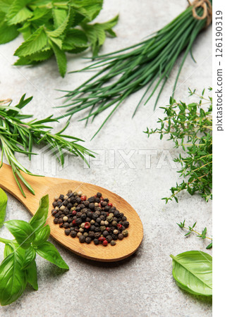 Fresh herbs and peppercorns resting on kitchen table 126190319