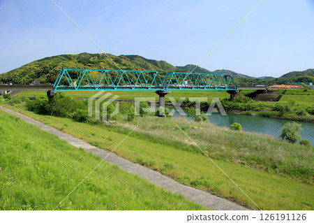 A vibrant turquoise steel bridge blending in with the fresh greenery 126191126