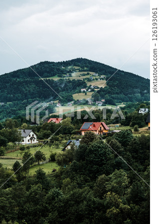 Scenic view of a hillside village with scattered houses among forested and agricultural slopes. Eco-tourism, sustainable tourism, cultural preservation, authentic village experiences... Scenic view of a hillside village with scattered houses among forested and agricultural slopes. Eco-tourism, sustainable tourism, cultural preservation, authentic village experiences... 126193061
