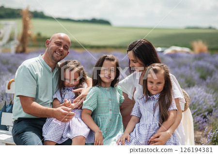 A beautiful family is resting in a lavender field. 126194381