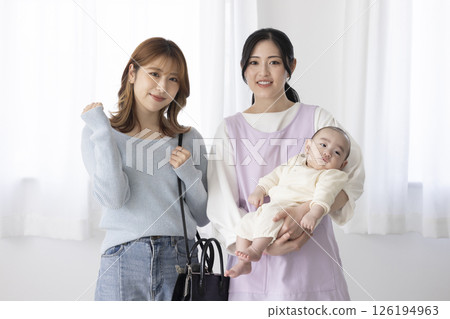 A working mother and a nursery teacher holding a baby A working mother and a nursery teacher holding a baby 126194963