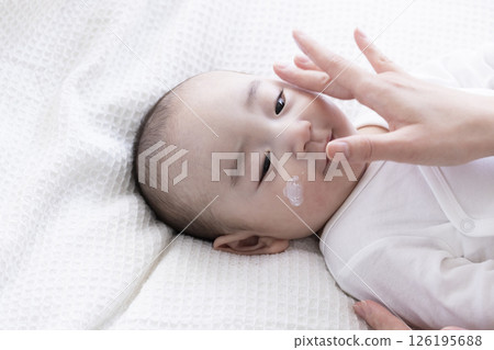 Mom's hands applying cream to baby Mom's hands applying cream to baby 126195688