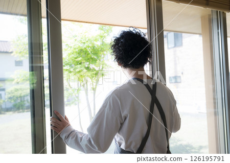 A man looking out the window, freshening up the air and cleaning A man looking out the window, freshening up the air and cleaning 126195791