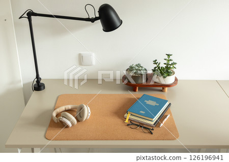 Modern minimalist workspace with lamp, notebooks, headphones, and succulent plants 126196941