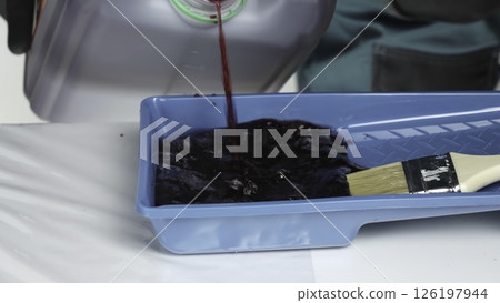 A person skillfully mixes red paint in a blue tray for art. Creative A person skillfully mixes red paint in a blue tray for art. Creative 126197944
