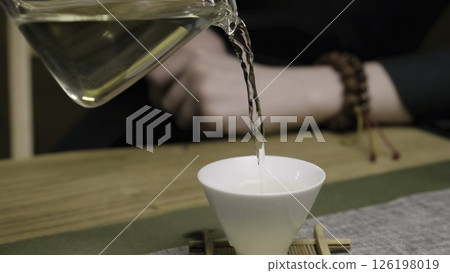 A serene moment of pouring tea into a white cup, evoking calm. Media A serene moment of pouring tea into a white cup, evoking calm. Media 126198019
