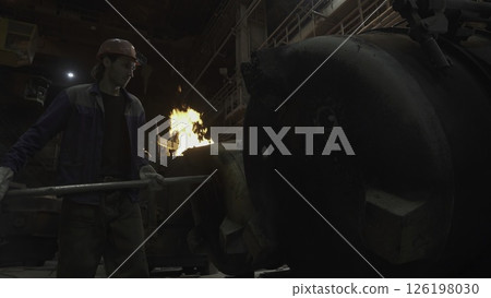 An Industrial Worker in a Foundry is Responsible for Igniting the Steel Manufacturing Process. Stock Clip An Industrial Worker in a Foundry is Responsible for Igniting the Steel Manufacturing Process. Stock Clip 126198030
