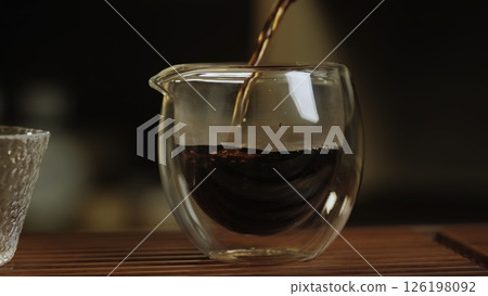 Pouring Tea into a beautiful and elegant Glass Teapot during a cozy and relaxing afternoon. Media 126198092