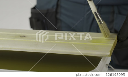 A tutorial shows treating wood with a yellow liquid, ensuring even coverage. Creative A tutorial shows treating wood with a yellow liquid, ensuring even coverage. Creative 126198095