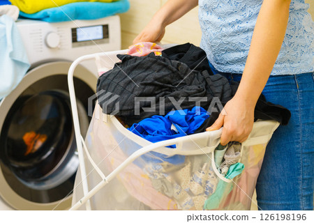 Woman holding laundry basket full of clothes 126198196