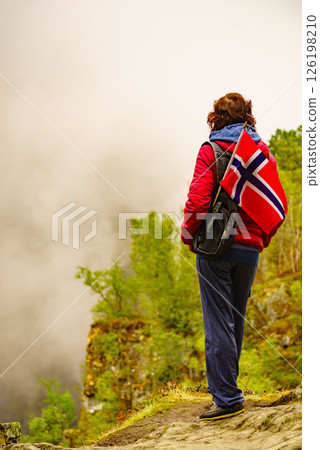 Tourist with norwegian flag in hazy mountains Tourist with norwegian flag in hazy mountains 126198210