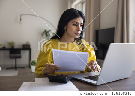 Millennial woman working with papers from home using notebook calculator 126198315