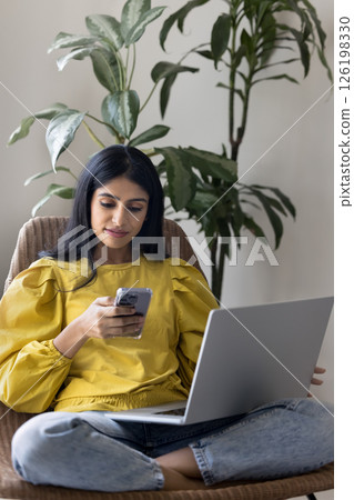 Woman zoomer relax on armchair using notebook and smartphone Woman zoomer relax on armchair using notebook and smartphone 126198330