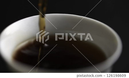 Pouring a rich and aromatic Coffee into a pristine White Cup against a Dark Background. Media 126198609