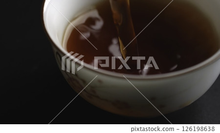 Gently Pouring Tea into a Beautifully Crafted Delicate Cup with a Creamy Swirl Design. Media Gently Pouring Tea into a Beautifully Crafted Delicate Cup with a Creamy Swirl Design. Media 126198638