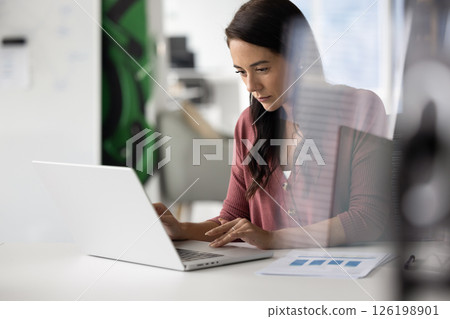 Busy young woman accountant sitting at desk working on notebook Busy young woman accountant sitting at desk working on notebook 126198901