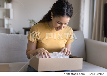 Smiling young female teenager sit on couch open carton box 126198964