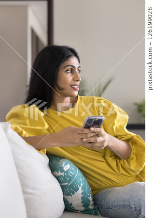 Beautiful young girl holding phone looking away with smile Beautiful young girl holding phone looking away with smile 126199028
