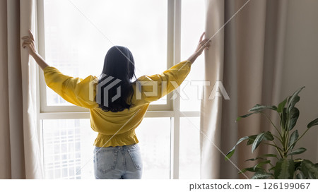 Successful confident millennial woman draw curtains on panoramic window Successful confident millennial woman draw curtains on panoramic window 126199067