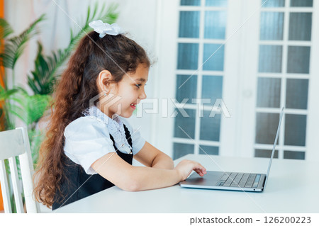 Schoolgirl Doing Homework At Table With Laptop 126200223