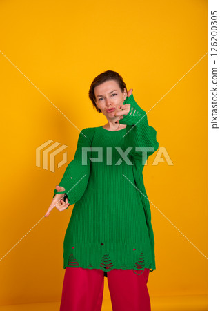40-year-old woman in green sweater on yellow background 126200305