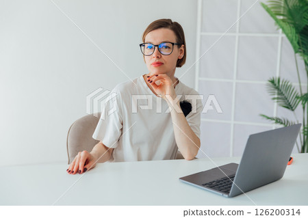 woman in glasses working at desk with laptop in office online woman in glasses working at desk with laptop in office online 126200314