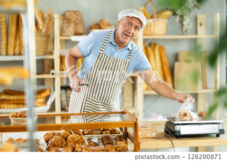 Elderly male seller puts pastries in bags and weighs Elderly male seller puts pastries in bags and weighs 126200871