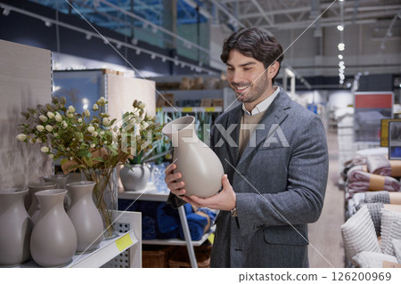 A man intently choosing a decorative vase in a stylish home decor store A man intently choosing a decorative vase in a stylish home decor store 126200969