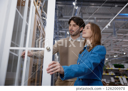 A young couple joyfully shopping for stylish furniture in a modern, vibrant store setting 126200978
