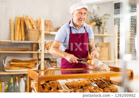 Elderly man seller puts croissants in bag Elderly man seller puts croissants in bag 126200982
